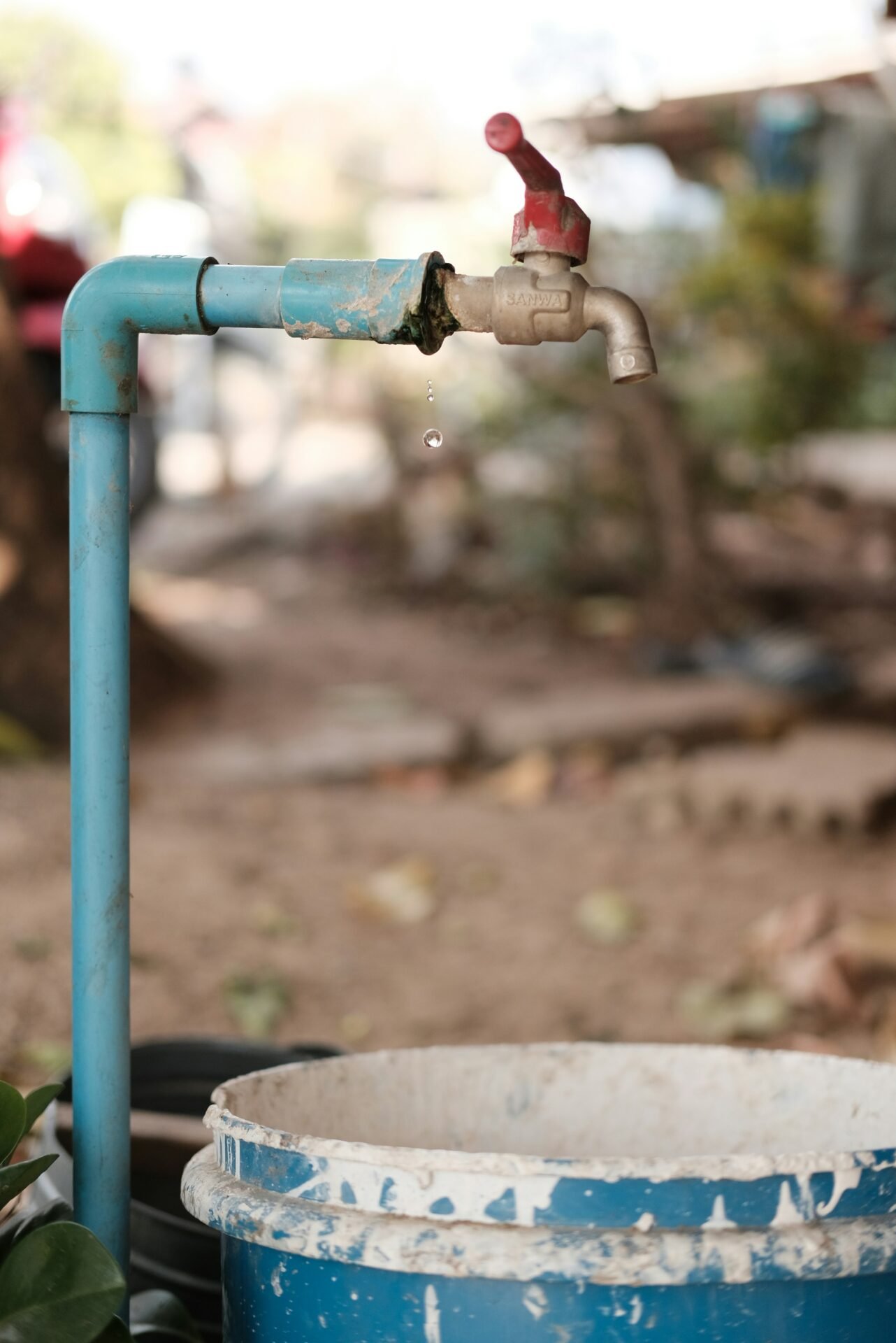 A water faucet with a bucket of water next to it